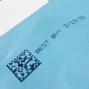 2D-Barcode und Mindesthaltbarkeitsdatum, aufgedruckt auf einer blauen, flexiblen Kunststoffverpackung mit dem MPERIA Axian XIJ-Drucker.