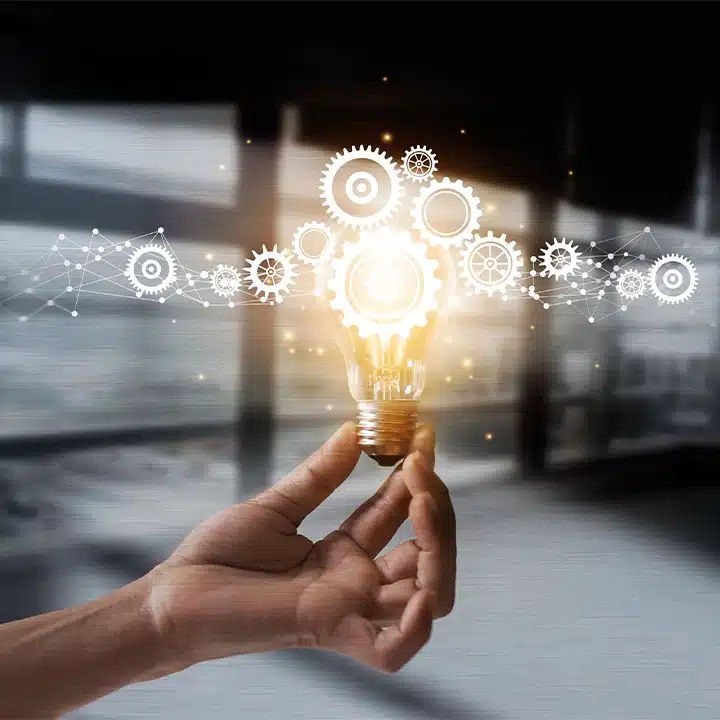 Konzeptbild zum Thema Innovation in der Fertigung, das eine leuchtende Glühbirne mit miteinander verbundenen Zahnrädern zeigt, die für Technik und Problemlösung stehen.