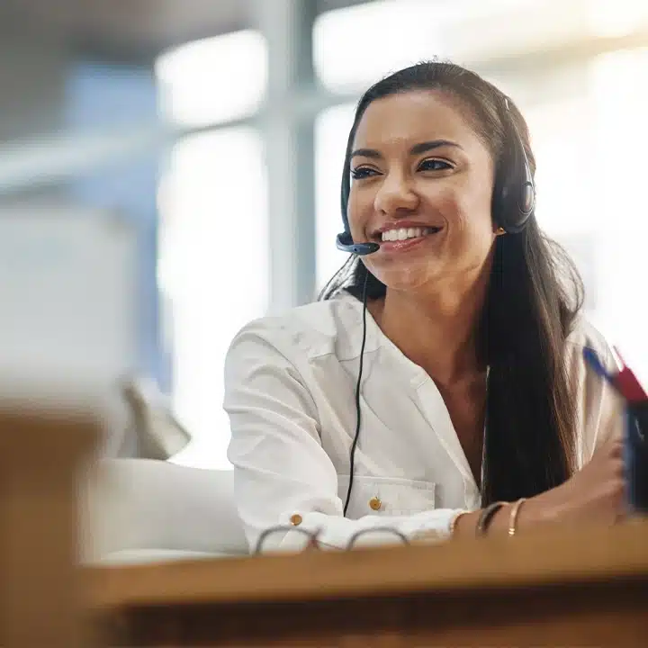 Ein Mitarbeiter des Kundensupport-Teams, der einem Kunden hilft, während er in einer modernen Büroumgebung ein Headset trägt.