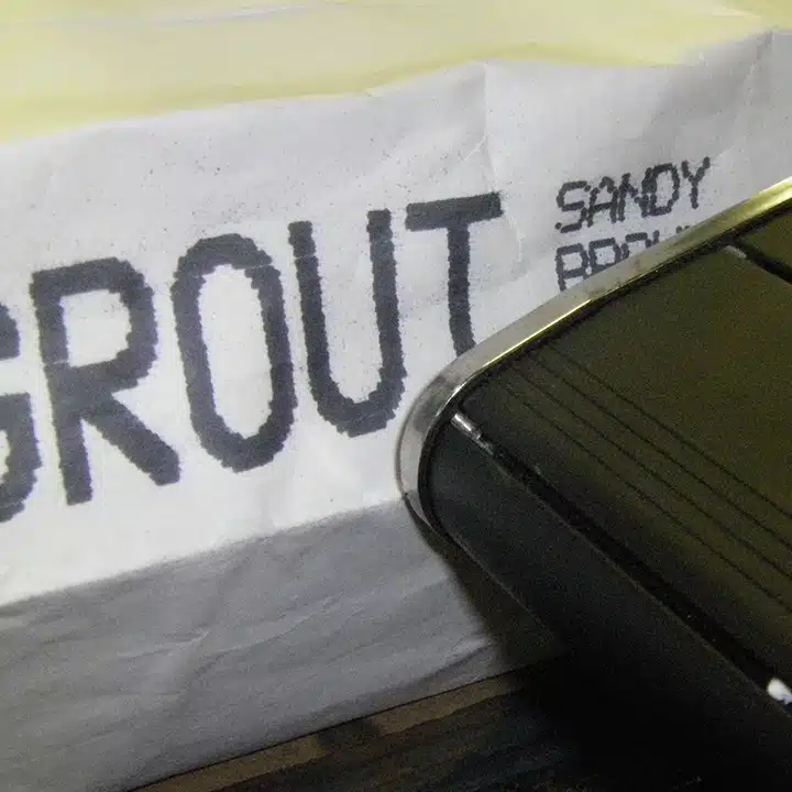 Ein Drucker MPERIA® V-Serie, der das Wort „Grout“ in großen Buchstaben mit schwarzer Tinte auf einen weißen Beutel druckt.