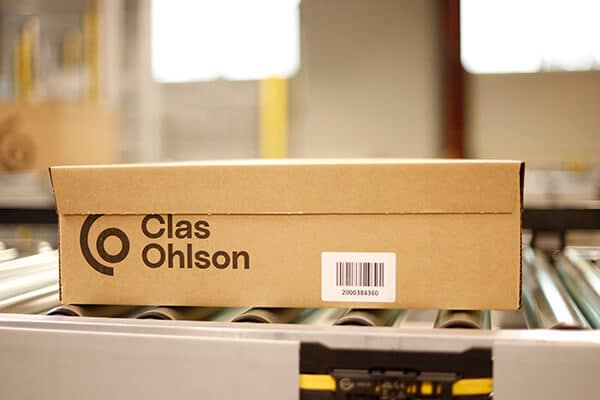 Eine Clas-Ohlson-Verpackung läuft über ein Förderband