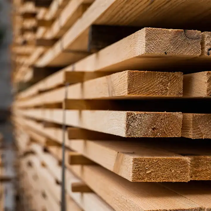 Nahaufnahme von gestapelten Holzbrettern, die die natürliche Maserung des Holzes und die Schnittkanten zeigen, in einem Holzlager.