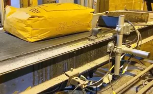 Gelbe Industrieverpackung mit aufgedruckten Identifikationscodes, die auf einem Förderband in einer Produktionsstätte transportiert wird.